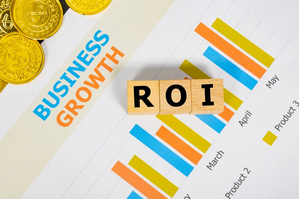 Wooden blocks spelling ROI on top of a business growth chart with rising bars, representing return on an SEO investment