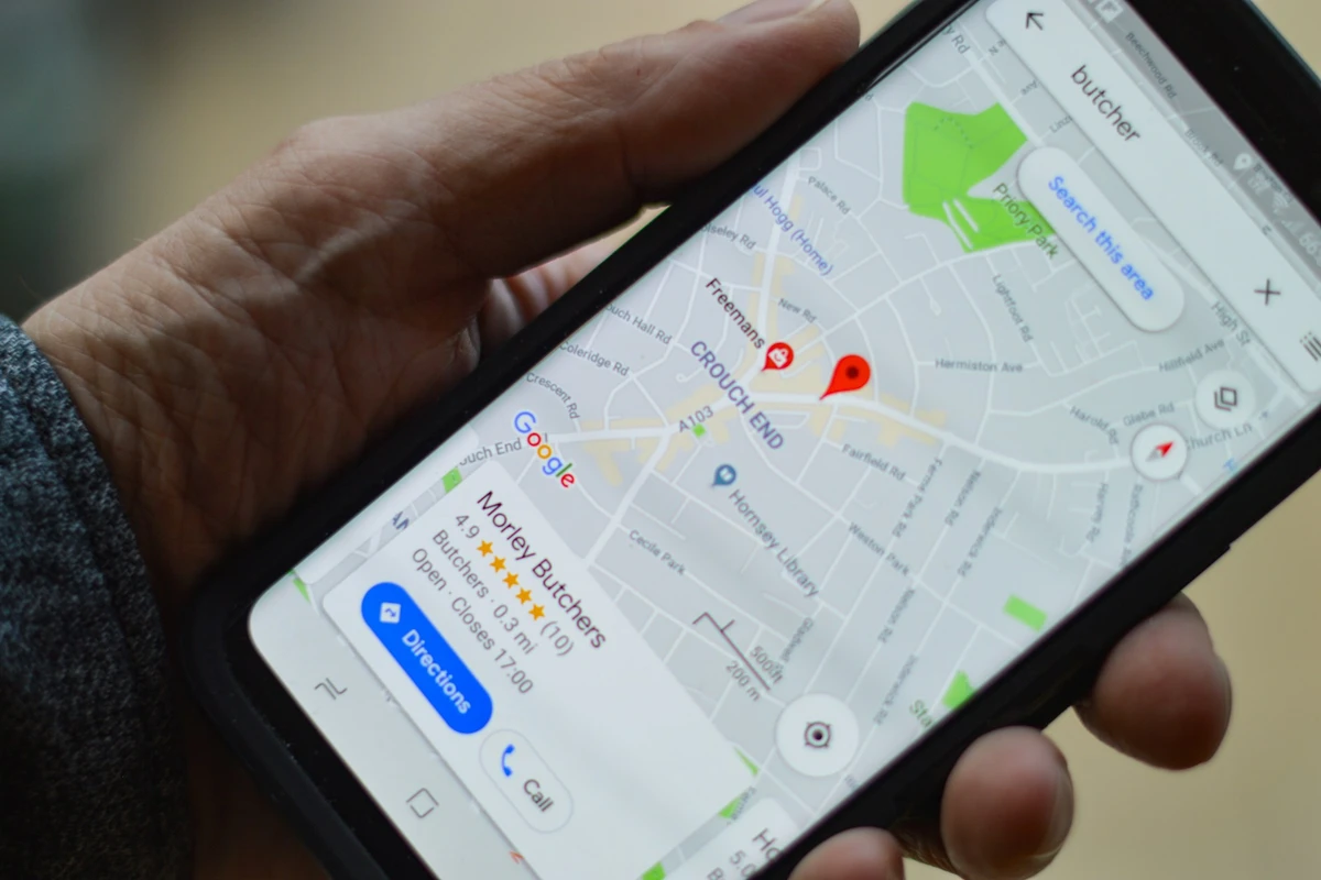 A phone showing a Google Maps listing for a local business with a 4.9 star rating, reviews, and directions and call buttons